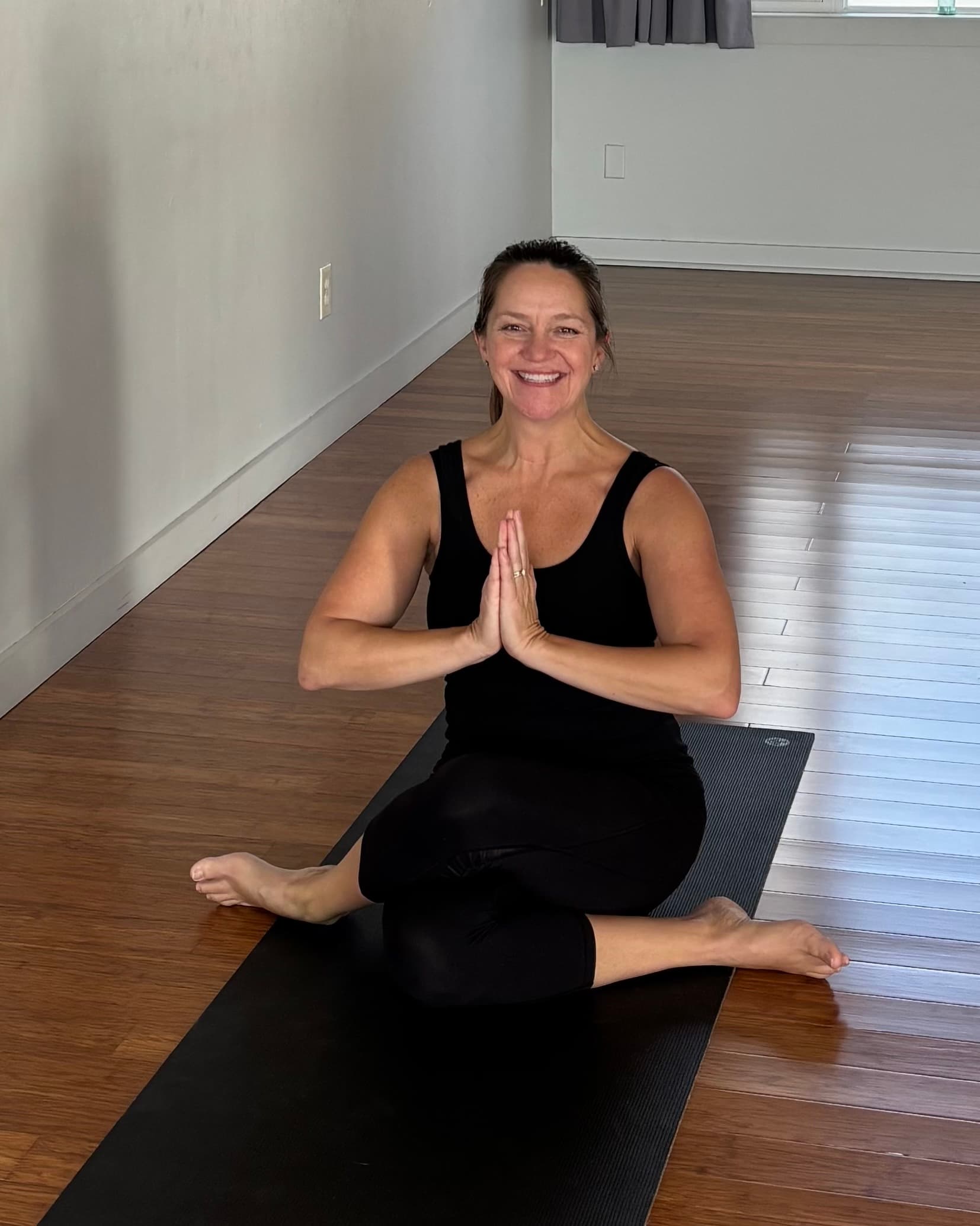 Amy Veno seated on her mat, hands at heart center